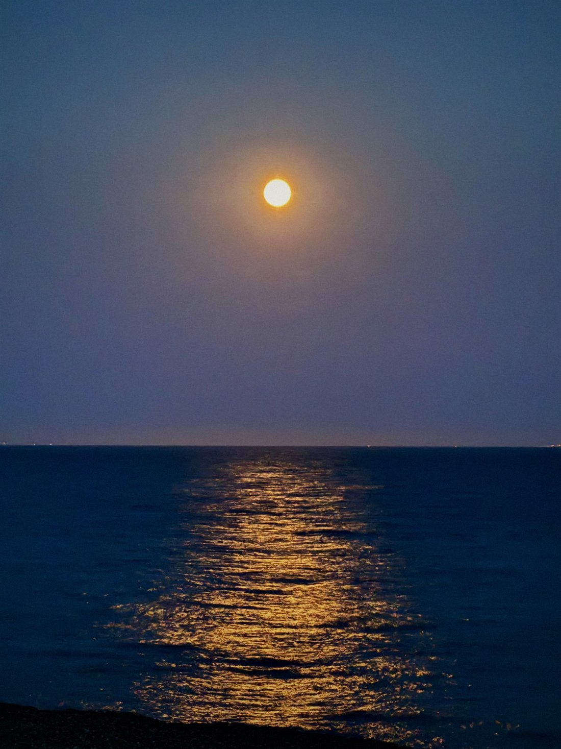 Full moon rising over the sea at Sandgate, its reflection running across the water to the shingle